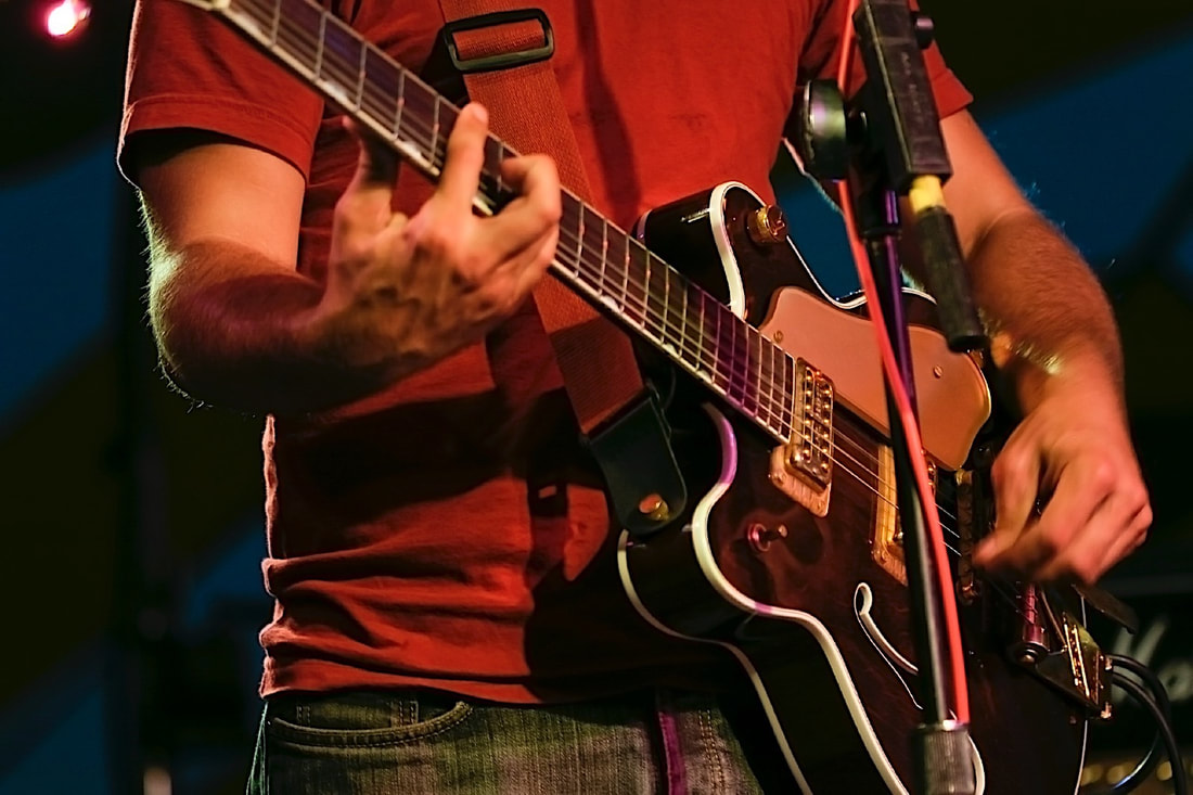 Guitarist playing a B-flat barre chord.