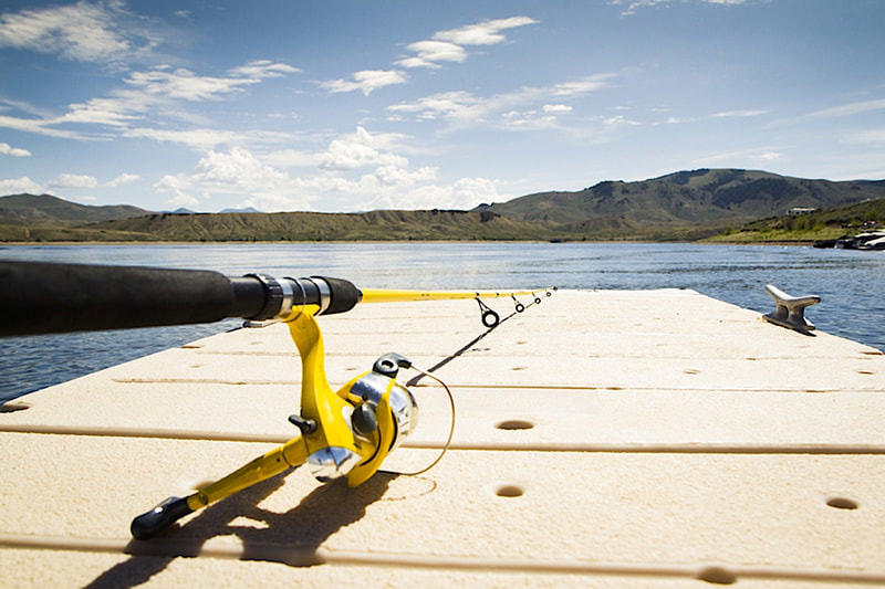 Fishing rod resting on a dock on a sunny day.